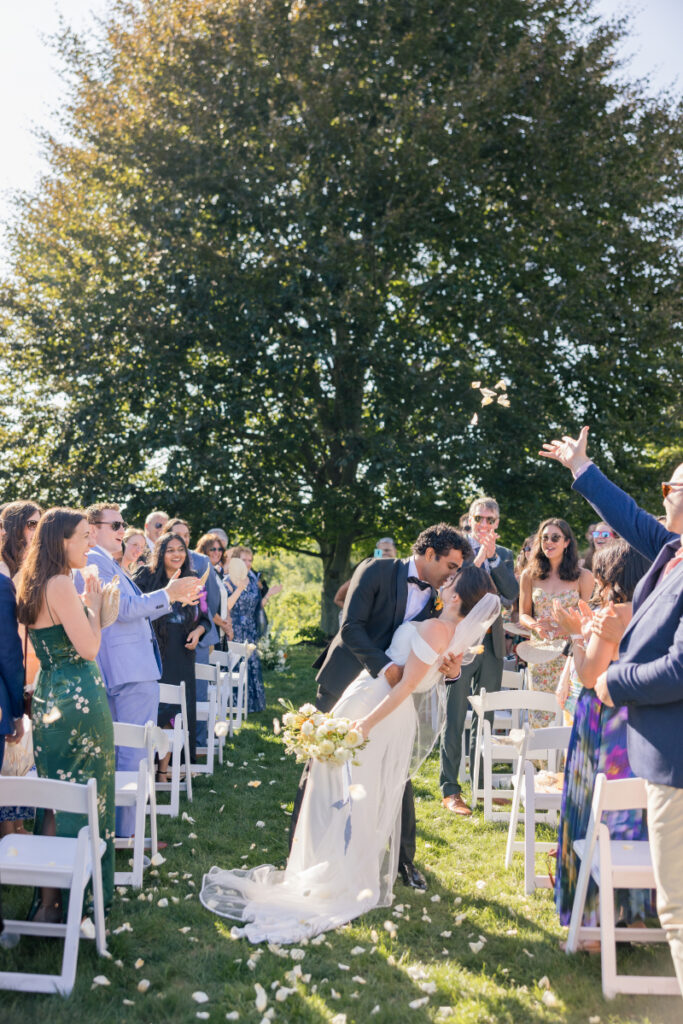 Just married couple kisses during ceremony recessional surrounded by guests at their wedding at Connemara House.