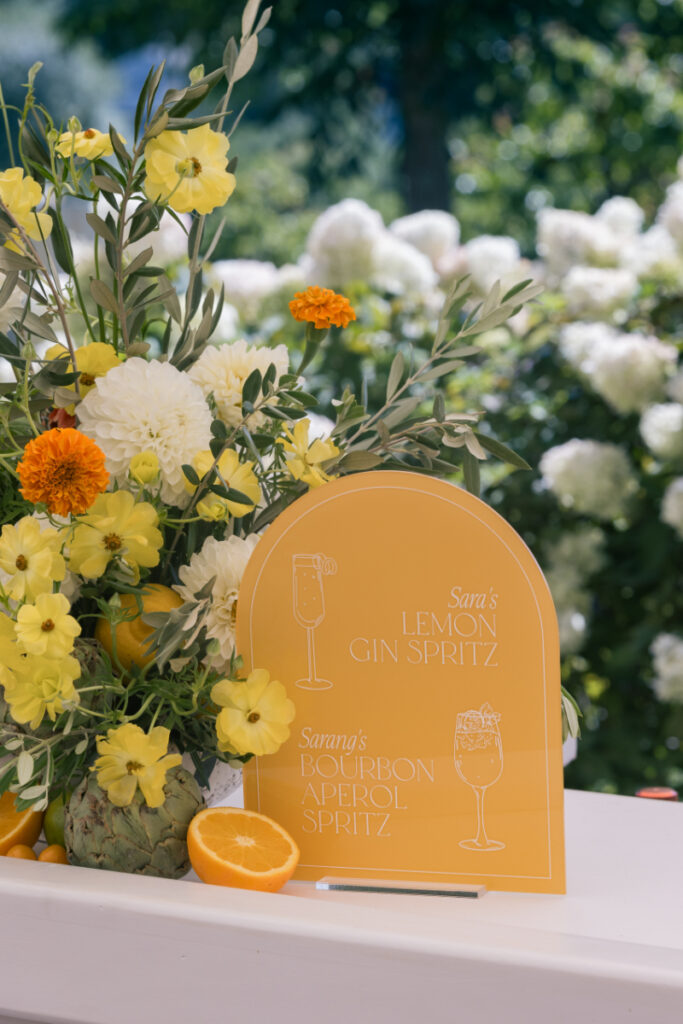 Citrus signature cocktail sign and florals at a colorful summer wedding at Connemara House.