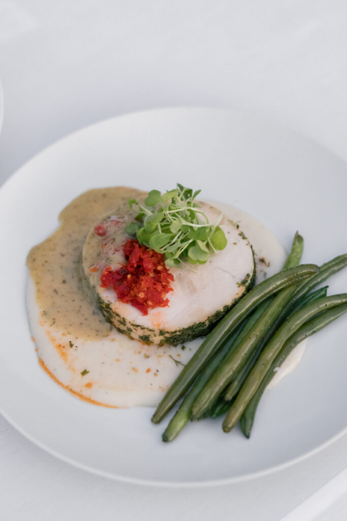 Plated dinner with stuffed chicken, green beans, and herb sauce served at the reception.