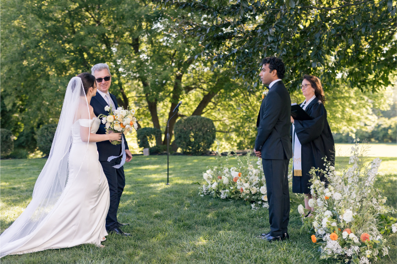 Bride walks down the aisle with her father during a garden ceremony at Connemara House wedding.