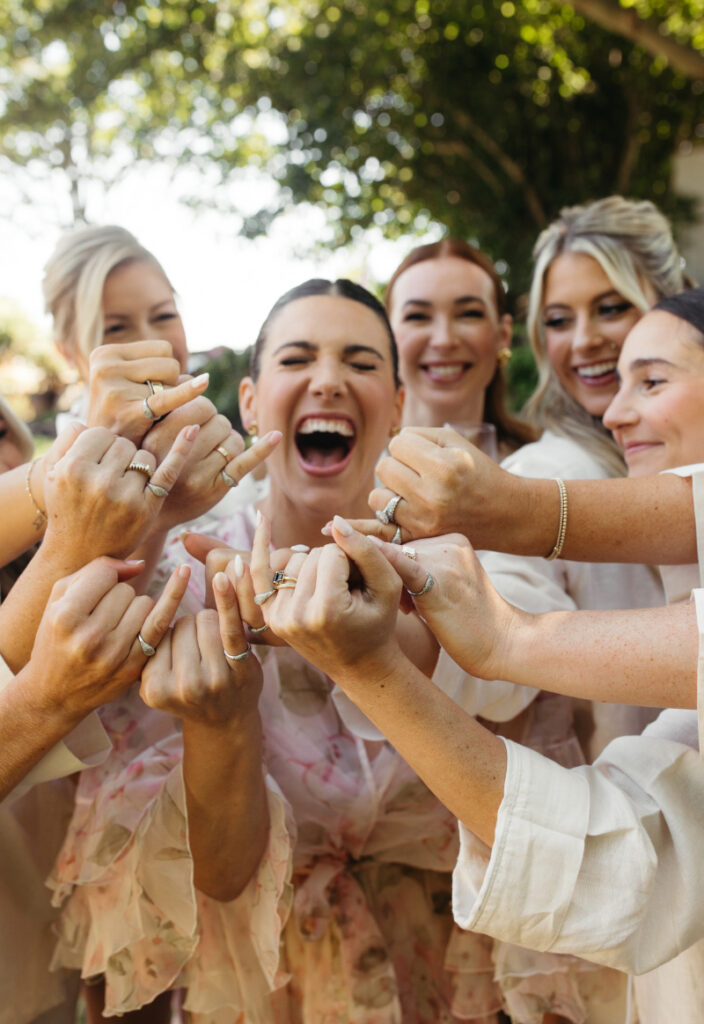 Bride laughing with bridesmaids while showing off engagement rings during a Block Island Wedding