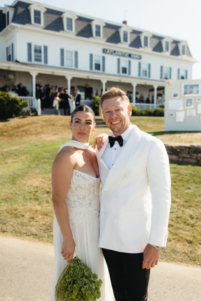 Bride and groom posing together outside seaside wedding venue after ceremony.
