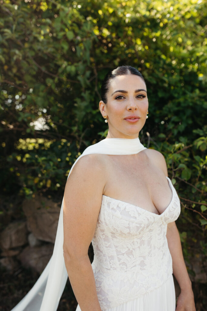 Bride portrait in lace gown and scarf during stylish coastal Block Island wedding with garden backdrop.
