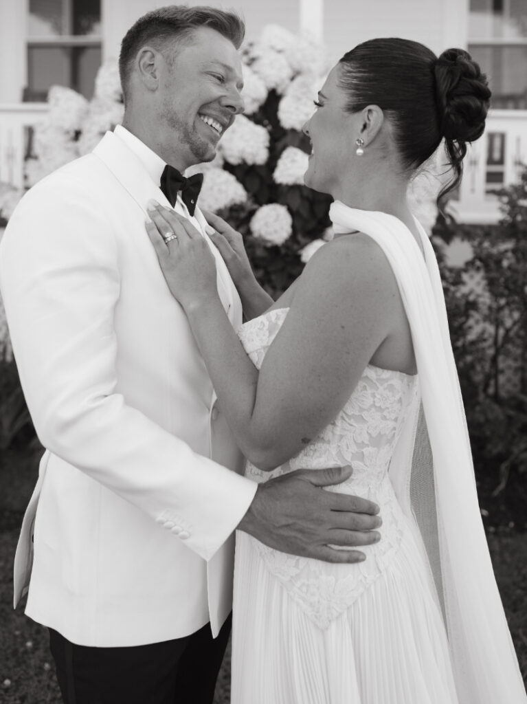 Bride and groom posing together outside seaside wedding venue after ceremony.