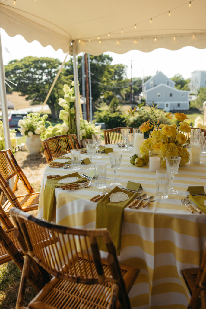 Reception table with yellow striped linens inside tent during coastal Italian inspired Block Island wedding.