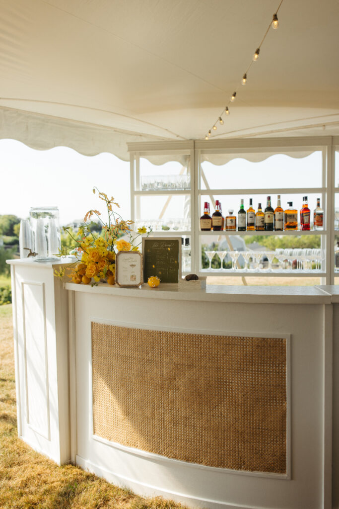 Curved cocktail bar with woven panel and backlit shelves during sunset cocktail hour.