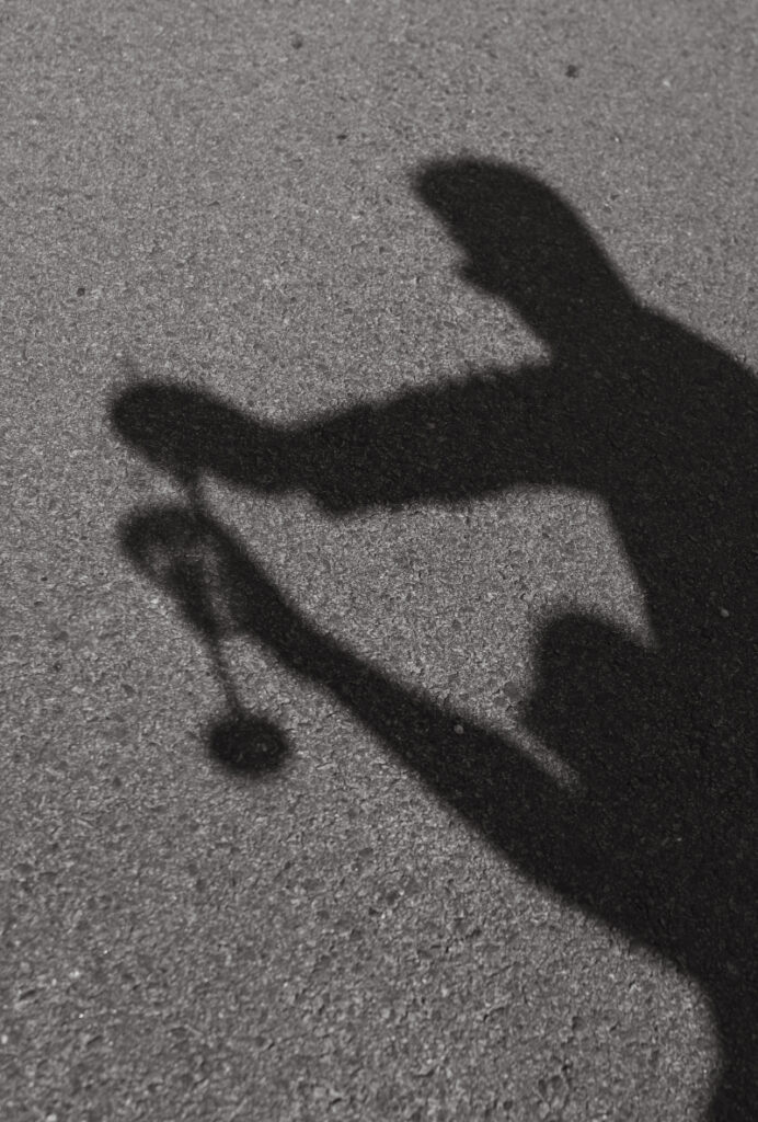 Shadows of guests raising champagne glasses during celebratory wedding moment on sunlit pavement.