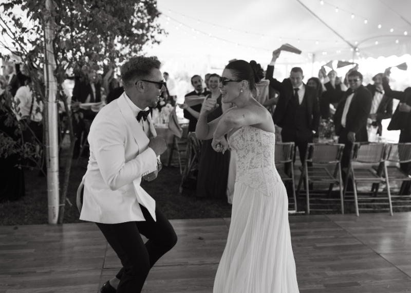 Guests cheering and waving napkins during energetic reception moment under string lights.