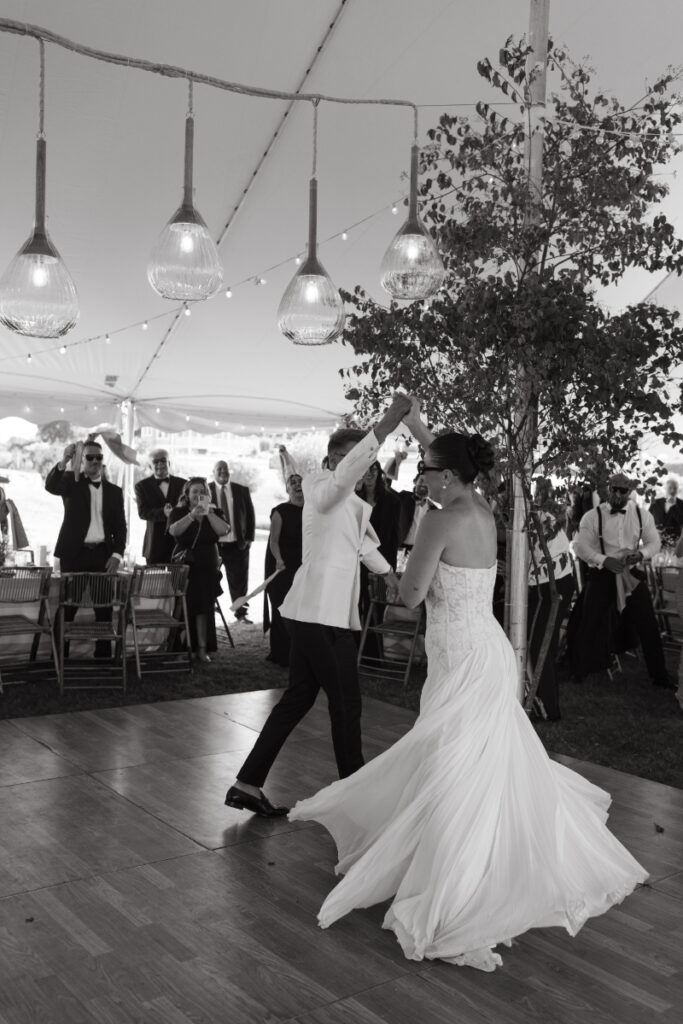 Bride wearing sunglasses laughing while dancing with groom during lively tented wedding reception at a Block Island Wedding