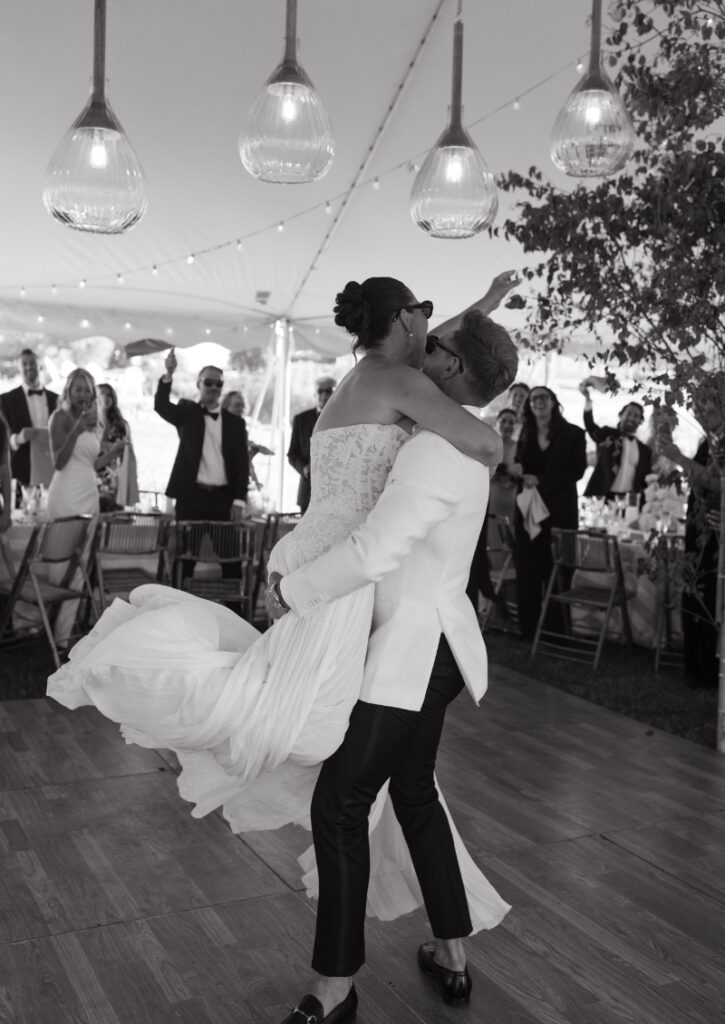 Bride twirling on the dance floor during first dance under hanging lights and greenery at a Block Island Wedding