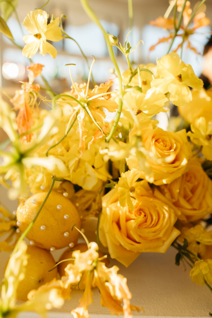 Yellow floral centerpiece with citrus and pearl accents during vibrant coastal Block Island wedding reception.