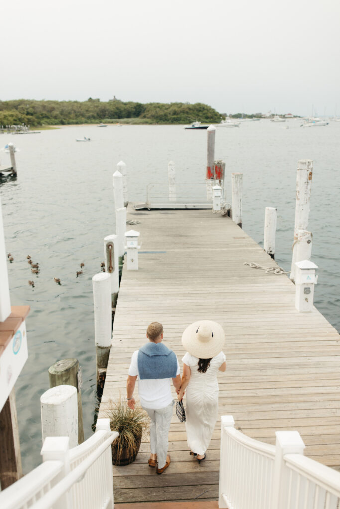 Couple walking down dock toward water during relaxed Block Island wedding weekend celebration.