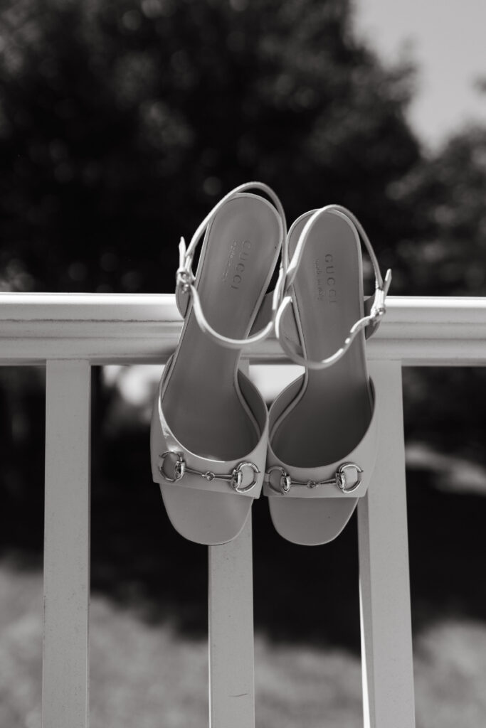 Bridal heels displayed on white railing during wedding detail photography.