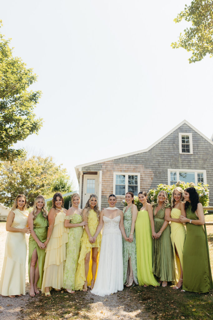 Bride with bridesmaids in yellow and green dresses posing outdoors before the ceremony.