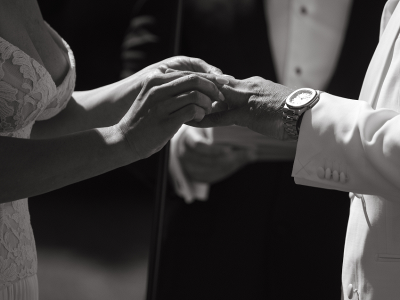 Close up of bride placing wedding ring on groom’s finger during ceremony.