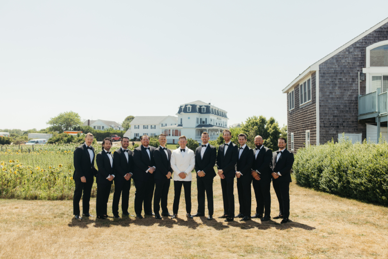 Groom and groomsmen posing together on coastal lawn before the Block Island Wedding