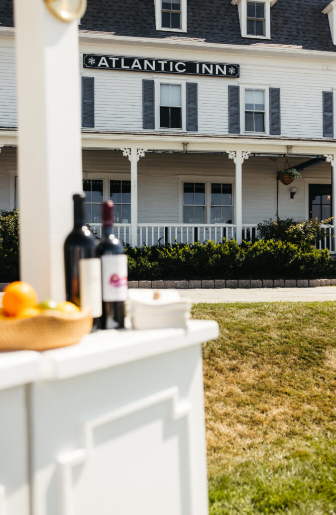 Cocktail bar setup with wine bottles and citrus placed in front of historic seaside inn.