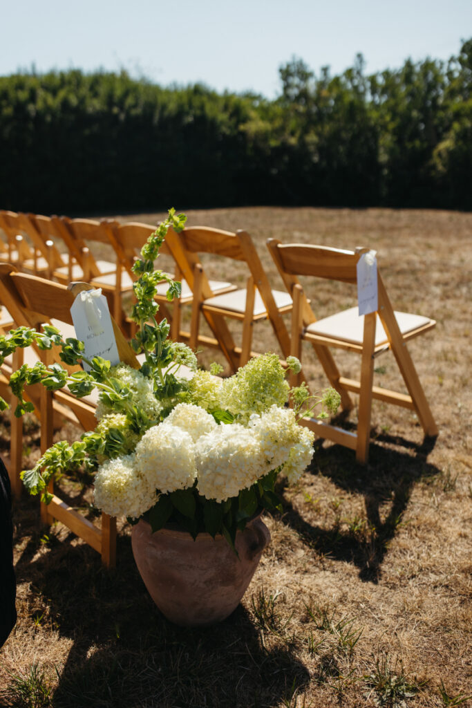 Ceremony chair details with hydrangea floral arrangement during elegant outdoor Block Island wedding.