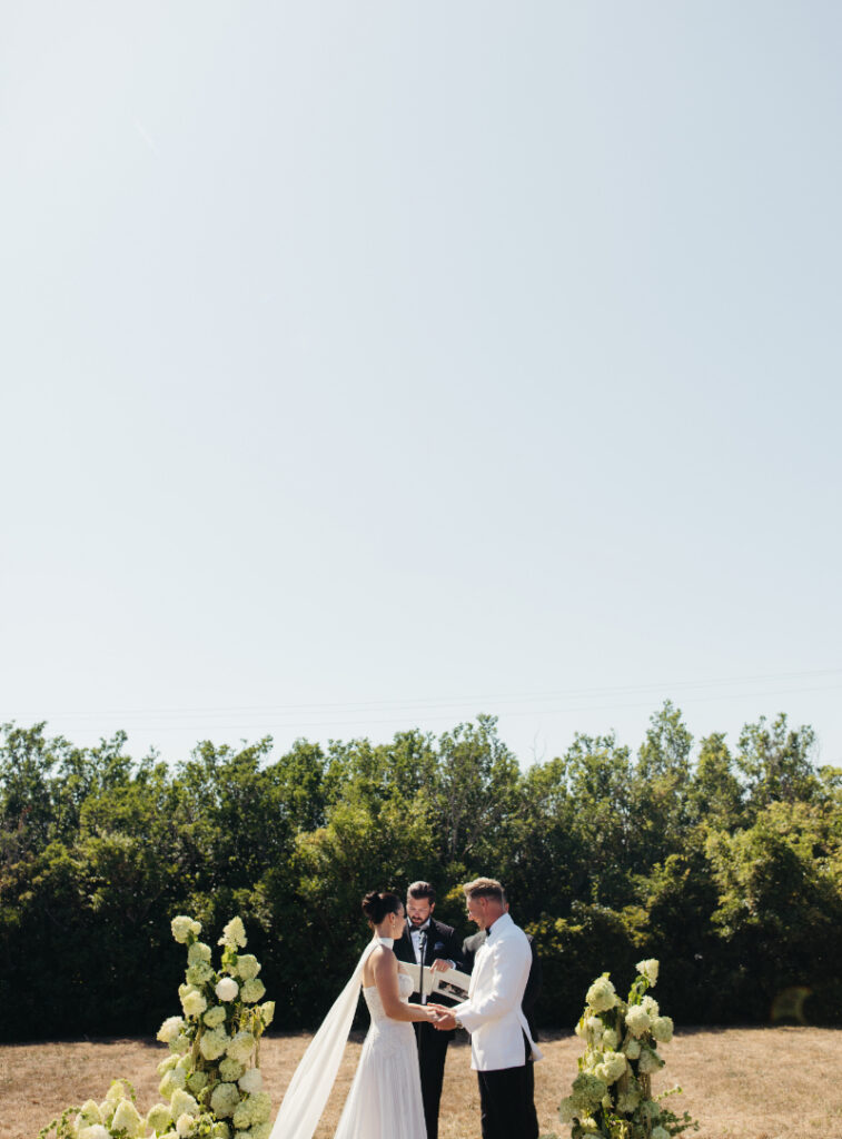 Bride and groom exchanging vows at outdoor garden ceremony with lush hydrangea florals.