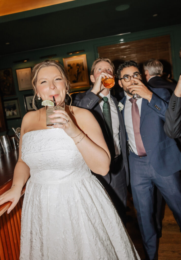 Bride and guests taking shots together at the bar during the reception