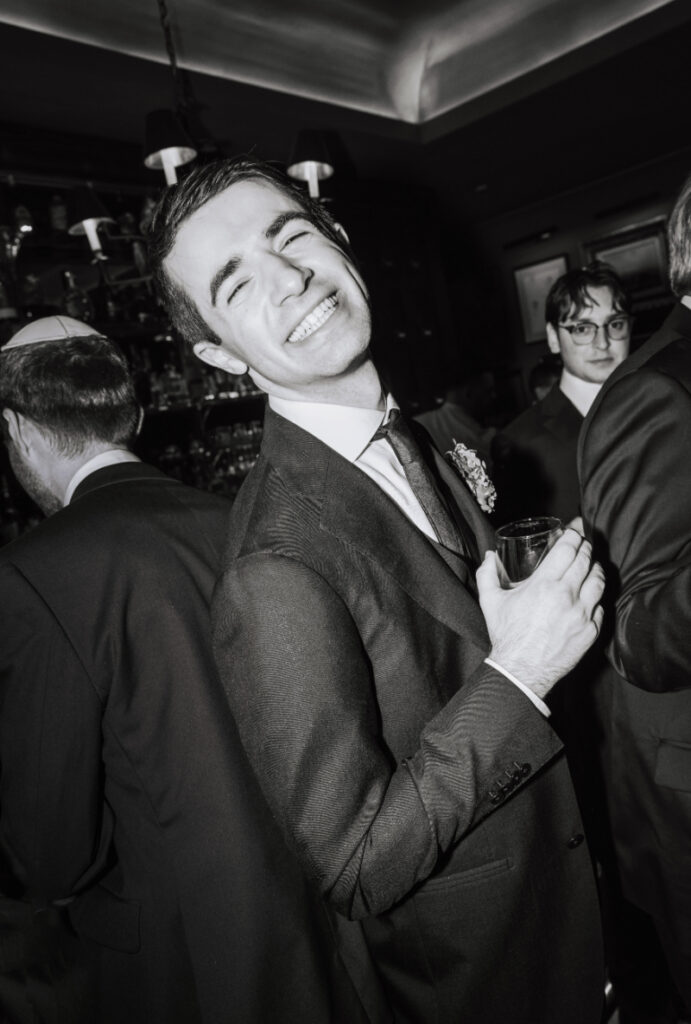 Guest smiling and holding a drink on the dance floor in a candid black-and-white moment
