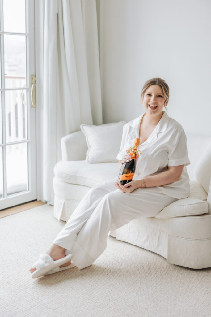 Bride in getting ready outfit holding champagne, relaxed morning moment styled by Newport wedding planner