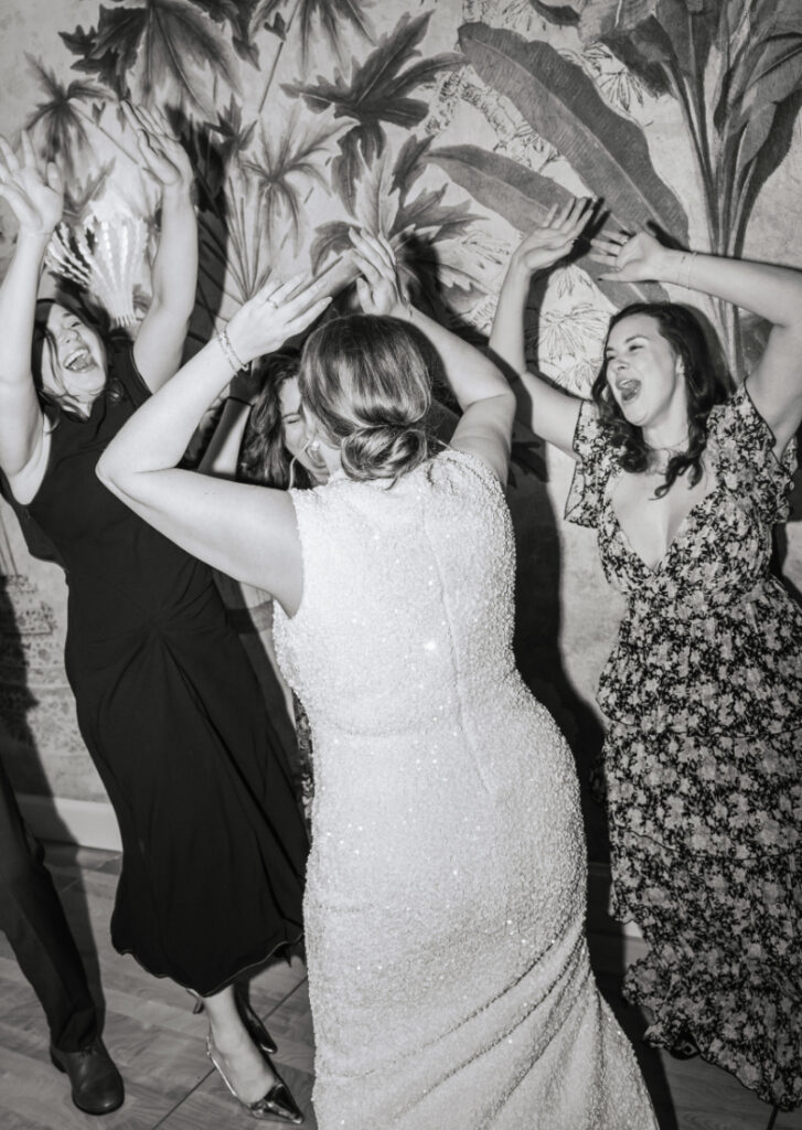 Bride dancing with guests, arms raised, during a lively moment on the dance floor