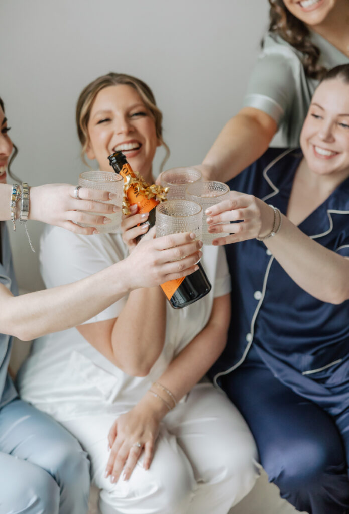 Bride and bridesmaids toasting champagne, joyful getting ready moment by Newport wedding planner