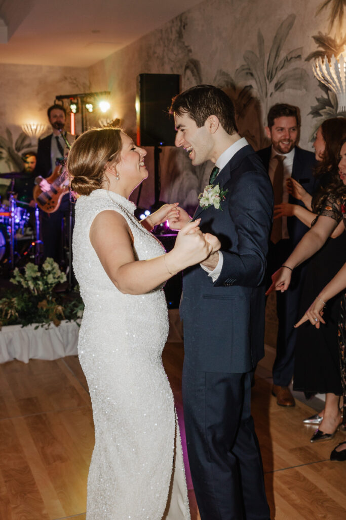 Couple dancing together on the dance floor surrounded by guests and live band