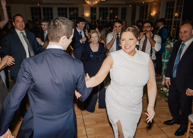Bride smiling and dancing with partner while guests watch and celebrate around them