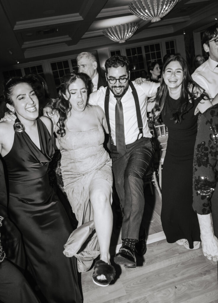 Group of guests dancing closely together with arms around each other during a high-energy moment