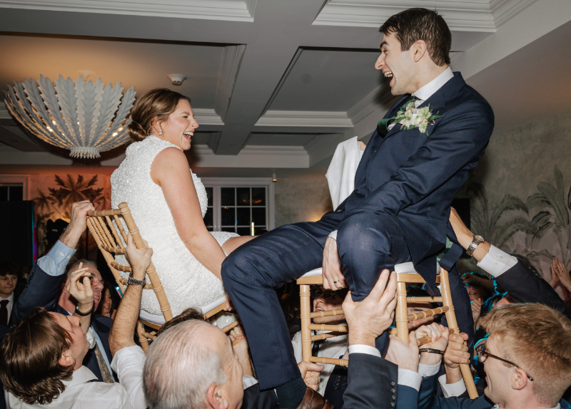 Bride and groom lifted on chairs during a lively dance floor tradition