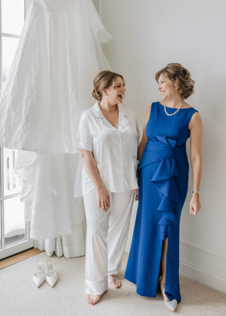 Bride with mother getting ready beside wedding dress, emotional morning moment by Newport wedding planner