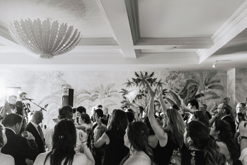Crowd of guests dancing together with hands raised during the reception