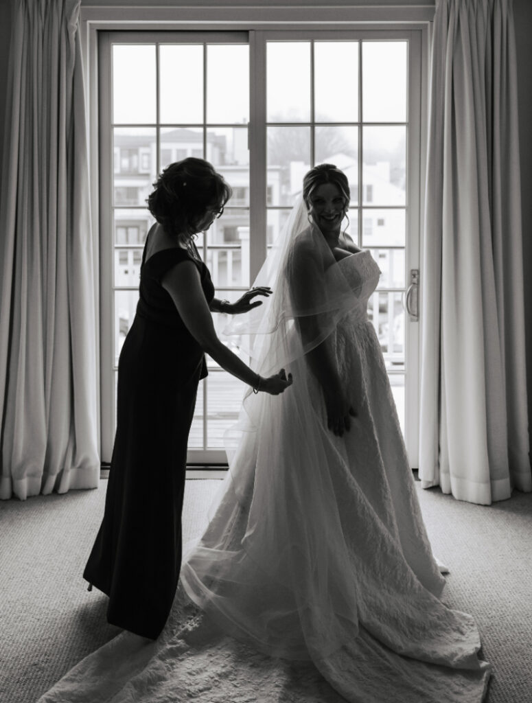 Bride with mother adjusting veil by window light, emotional bridal moment by Newport wedding planner