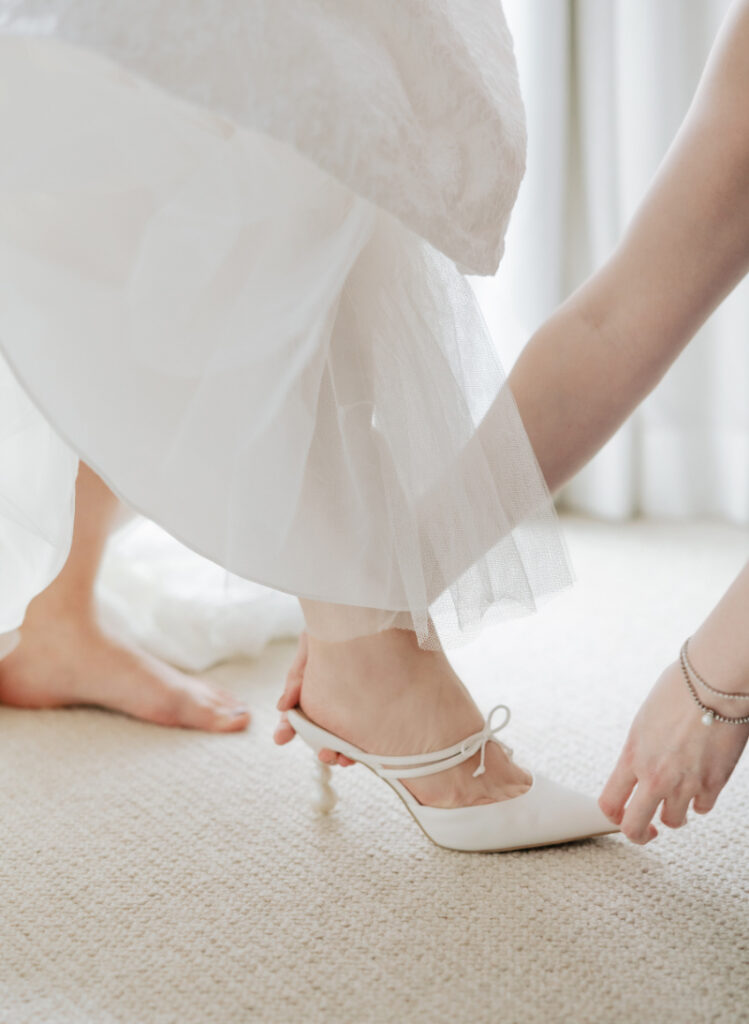 Bride putting on wedding heels, soft bridal detail moment styled by Newport wedding planner