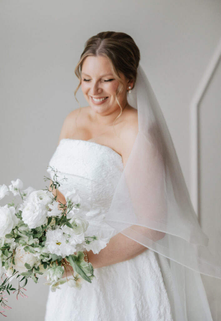 Bride holding white bouquet in strapless gown, soft and romantic Newport wedding portrait