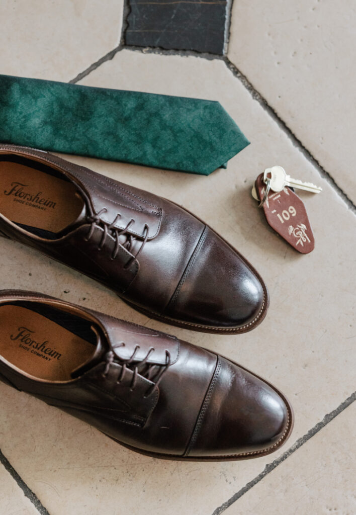 Groom details with brown shoes, green tie, and key tag, classic Newport wedding styling