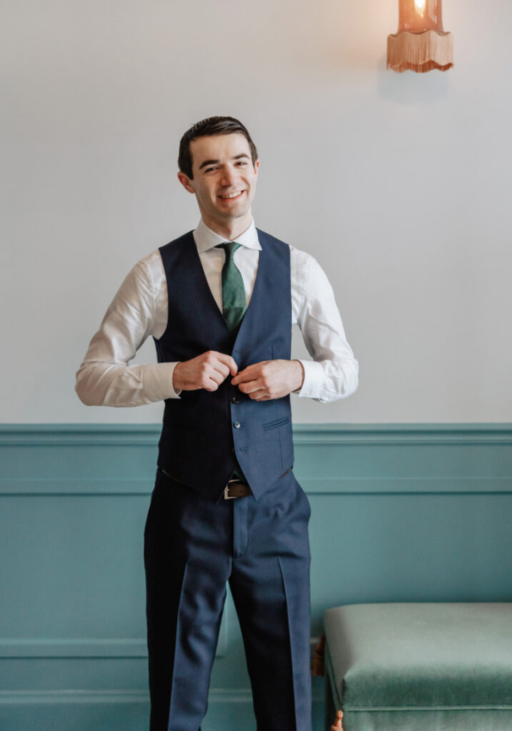 Groom adjusting suit with green tie, classic and polished Newport wedding style