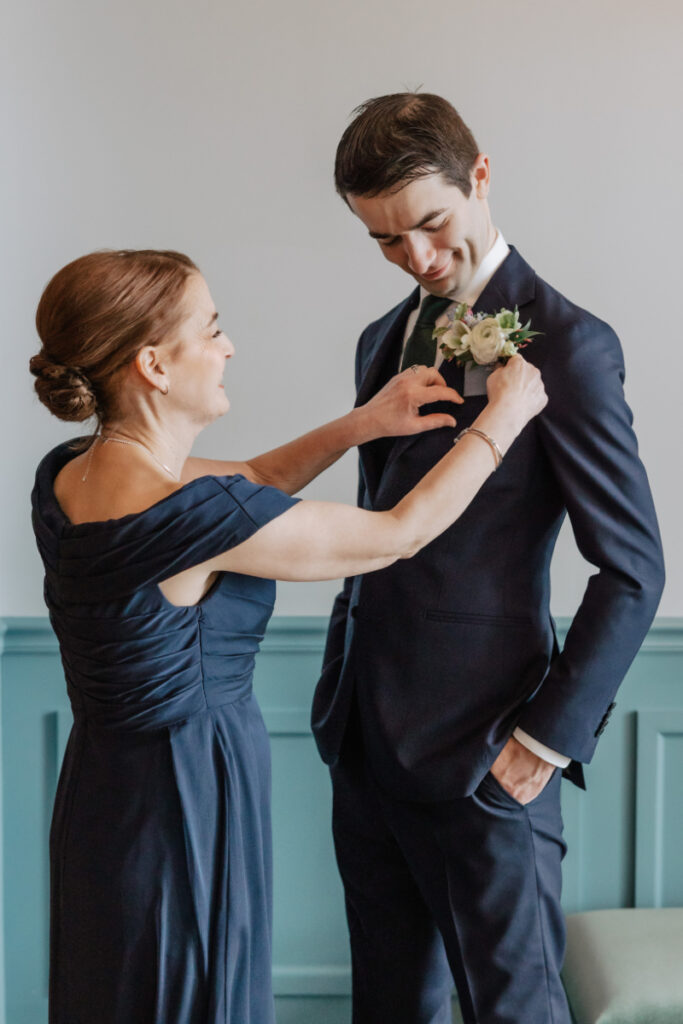 Groom’s mother pinning boutonniere, meaningful getting ready moment during Newport wedding