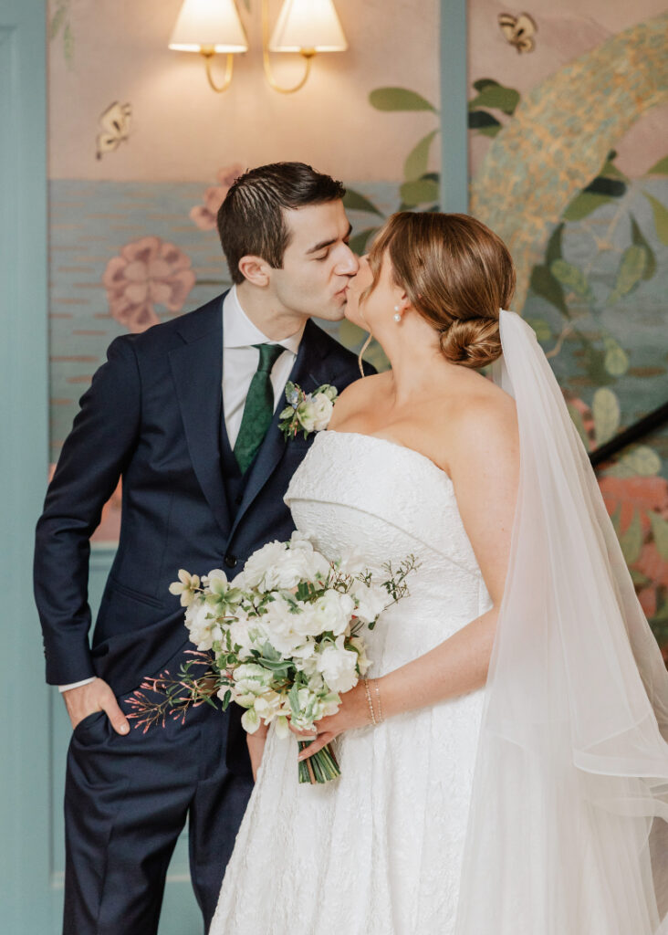 Couple sharing a kiss indoors with soft lighting, intimate moment during Newport wedding celebration