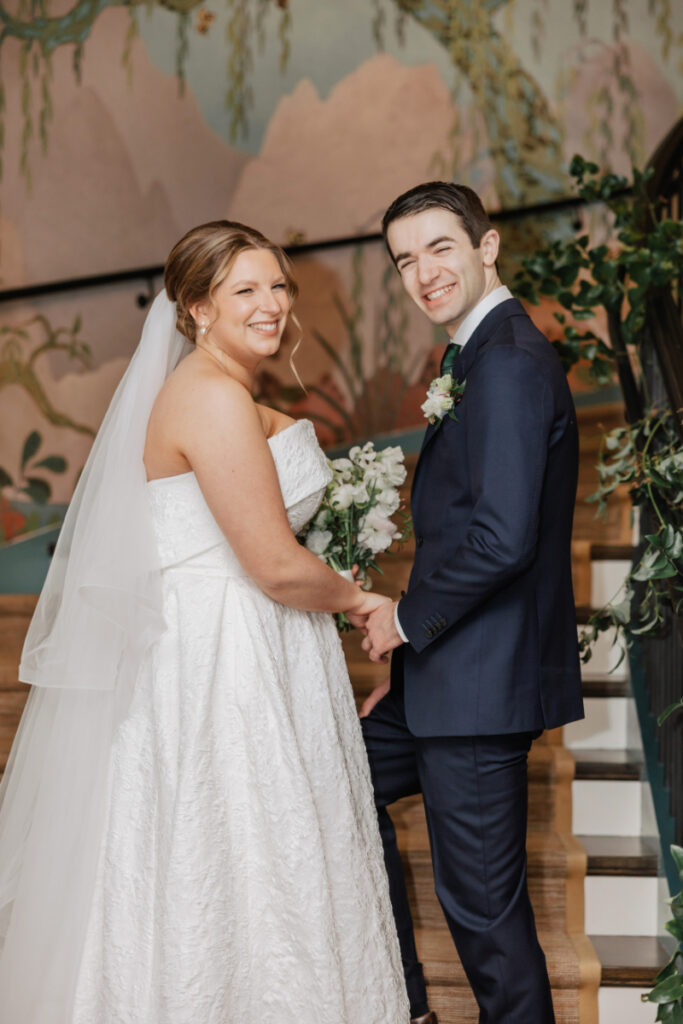 Bride and groom smiling together on staircase, classic portrait moment during Newport wedding