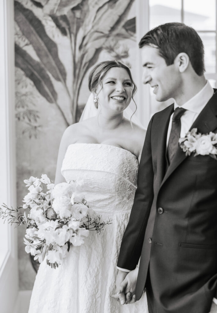 Bride and groom smiling and holding hands, candid black and white Newport wedding portrait