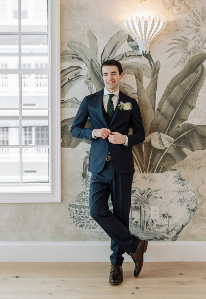 Groom portrait against mural wall, classic tailored style captured during Newport wedding preparations