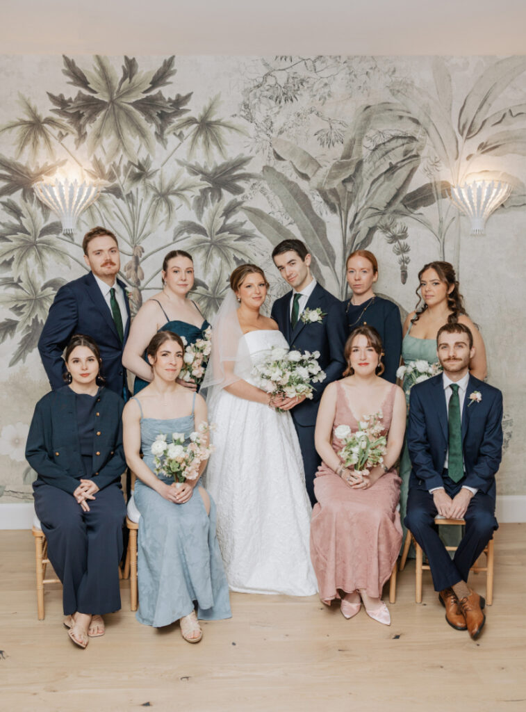 Full wedding party portrait with layered tones and florals, editorial-style Newport wedding group photo