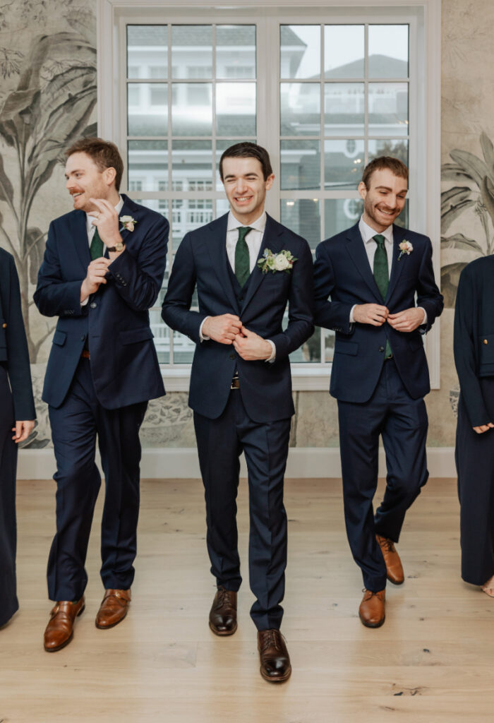 Groomsmen walking and laughing in navy suits, relaxed and stylish Newport wedding portrait