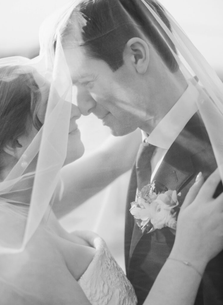 Romantic close-up under veil with soft light, intimate newlywed moment captured during Newport wedding