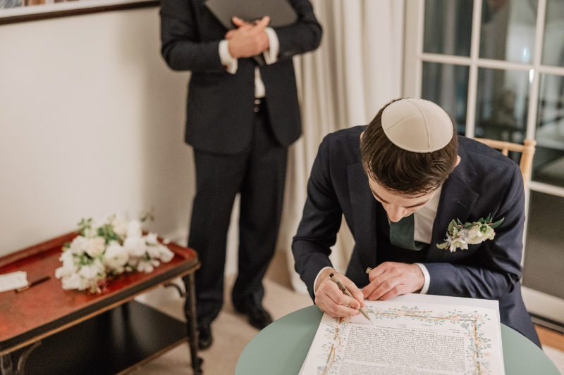 Groom signing ketubah during ceremony, meaningful tradition captured in quiet focused moment