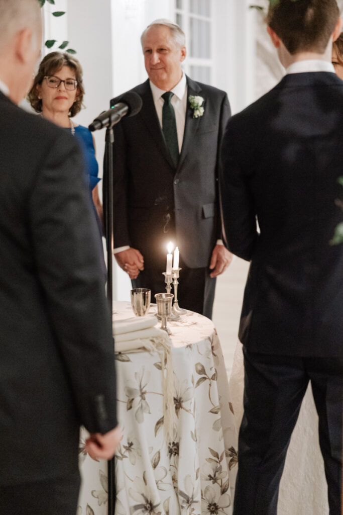 Couple standing with family during ceremony blessing, intimate moment with candlelight and meaningful tradition