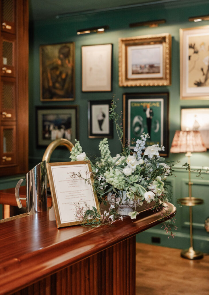 Escort card display styled with soft florals and warm wood tones, seamlessly blending into the overall design of the space